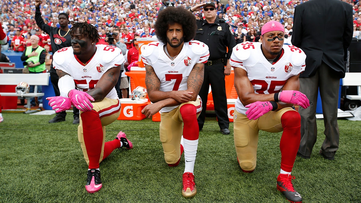 Colin Kaepernick kneeling with Eli Harold and Eric Reid on the sideline during the anthem