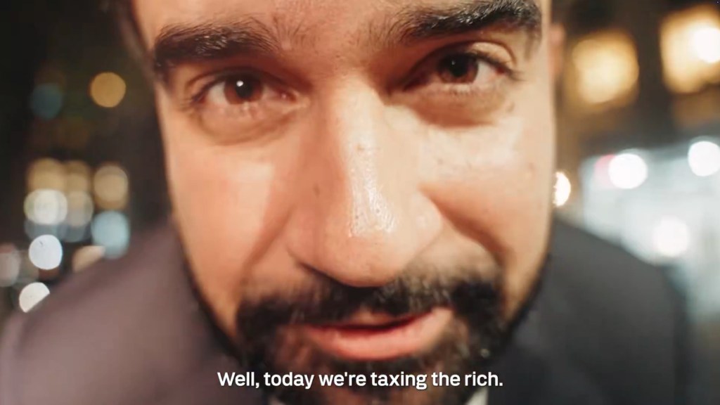 A screenshot closeup of Zohran Mamdani's face with caption, "Well, today we're taxing the rich."
