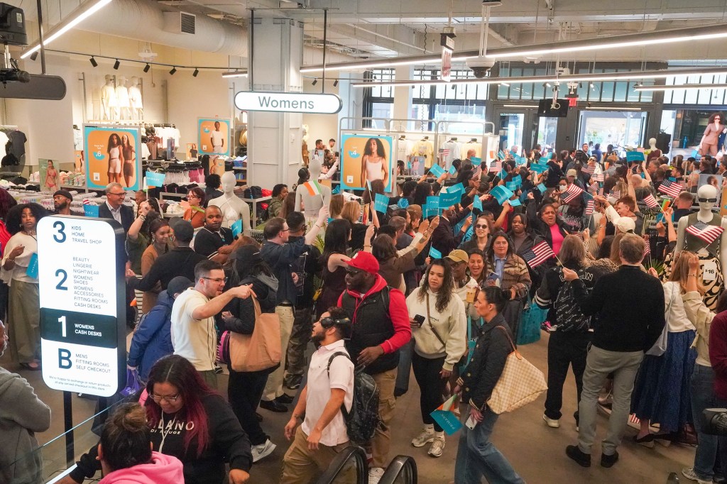 Customers celebrating the opening of a Primark store in Manhattan, waving small Primark and American flags.