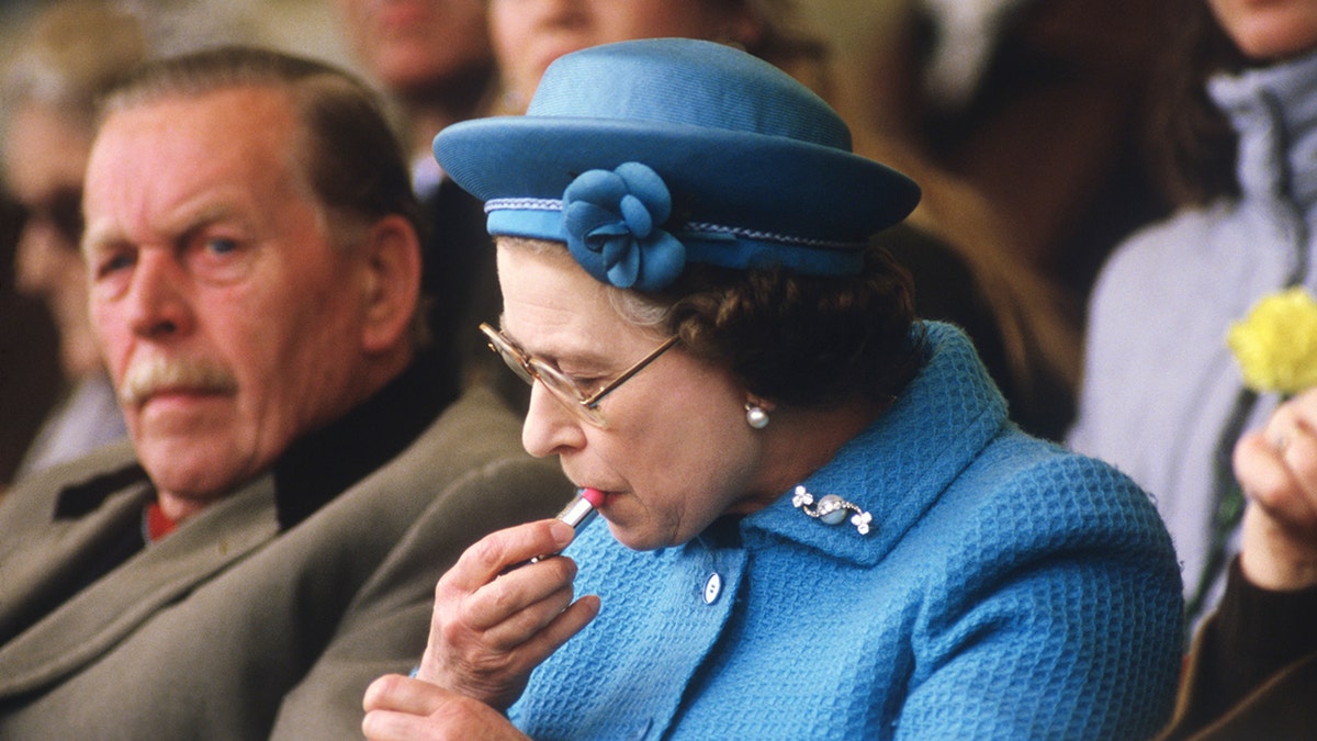 Queen Elizabeth II putting on lipstick in the Royal Box at the Windsor Horse Show