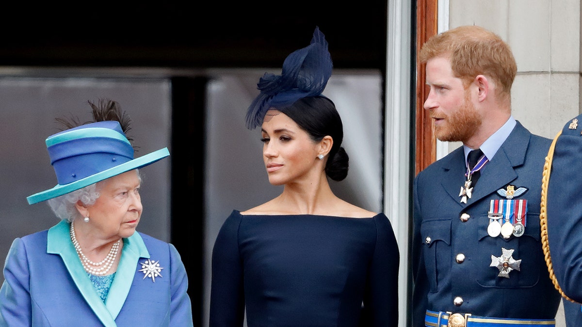 Queen Elizabeth II, Meghan, Duchess of Sussex, and Prince Harry watching a flypast from Buckingham Palace balcony