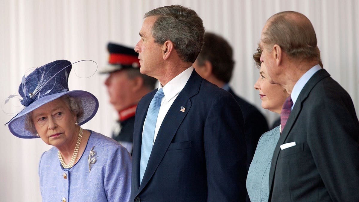 Queen Elizabeth II looking anxiously at Prince Philip during a ceremony at Buckingham Palace