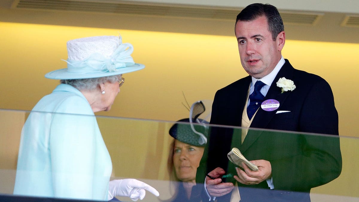 Queen Elizabeth II talking with Deputy Private Secretary Edward Young in royal box at Ascot Racecourse