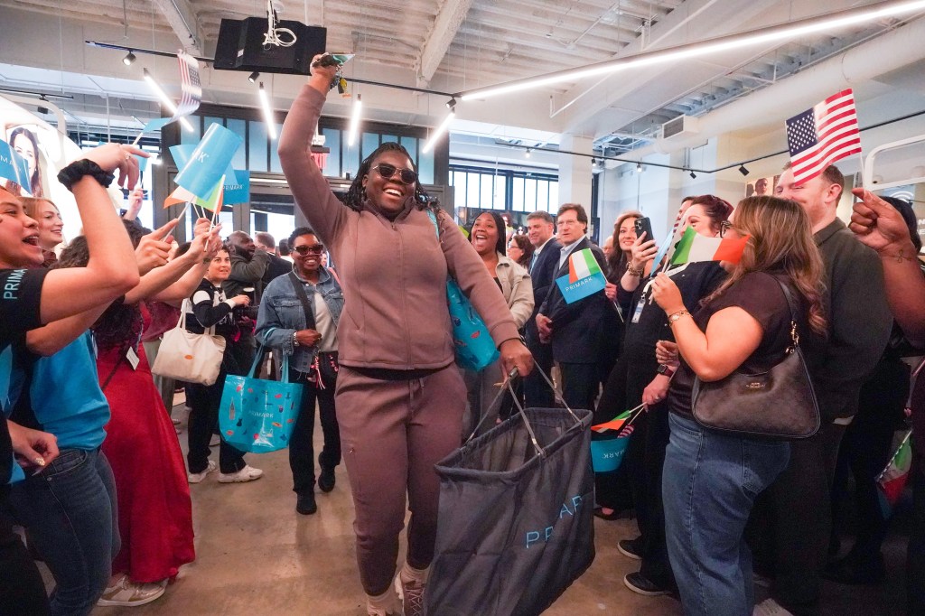 Quintasha Watson, an MTA bus operator, cheering with keys raised, among other customers waving flags at a Primark store opening.