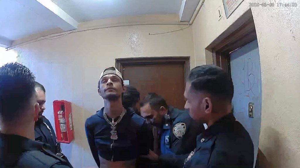 Anthony Orozco in a cropped hoodie and baseball cap, surrounded by four police officers during his arrest.