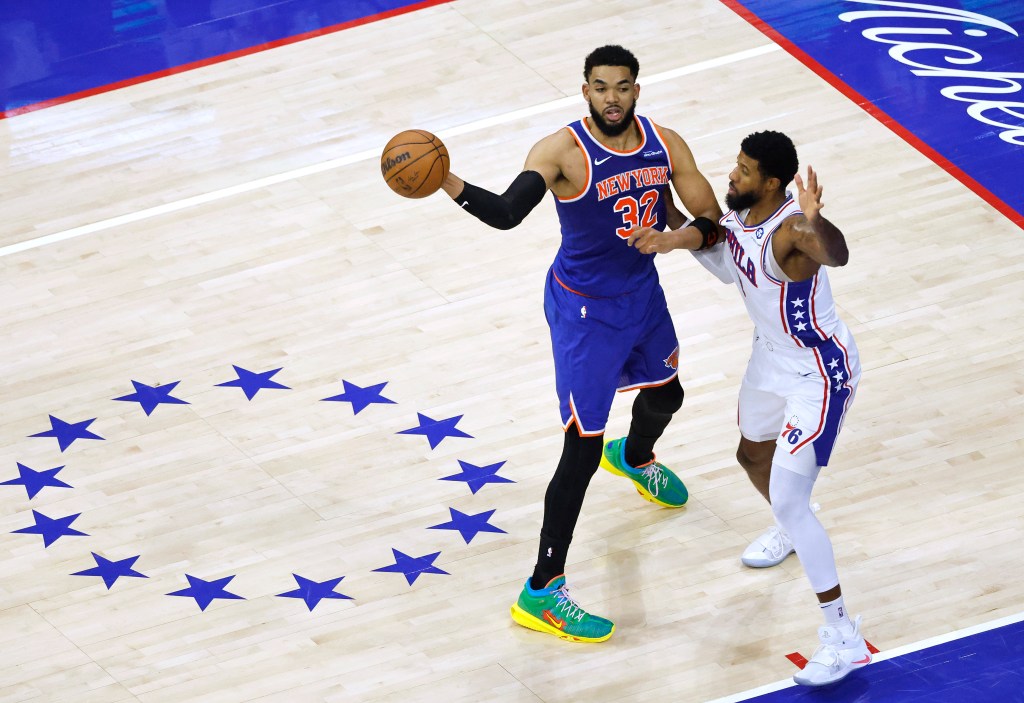 New York Knicks center Karl-Anthony Towns (32) passes the ball as Philadelphia 76ers forward Paul George (8) defends.