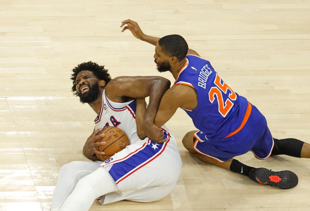 76ers center Joel Embiid (21) grimaces as he and Knicks wing Mikal Bridges (25) fight for control of the ball during Game 4 of the second round on May 10, 2026.