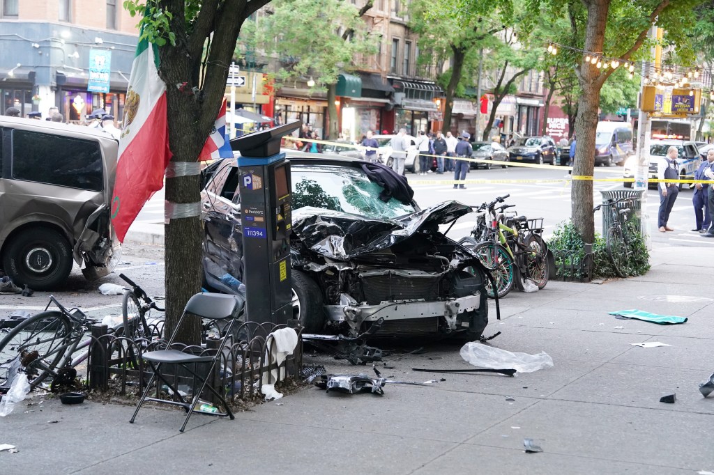 A car crashed onto the sidewalk in New York, with a damaged front end, parked next to a tree with a Mexican flag tied to it.