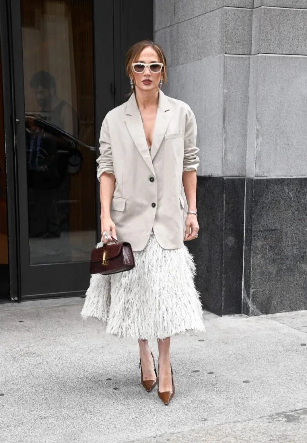 Jennifer Lopez paired a structured beige blazer with a textured fringe skirt for a polished city look.