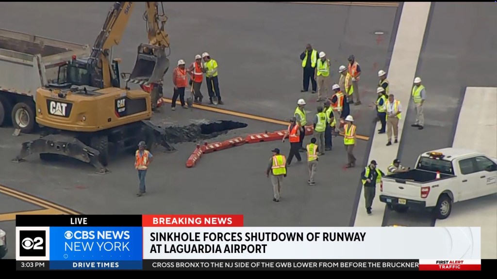 A sinkhole on a LaGuardia Airport runway with construction workers and equipment.