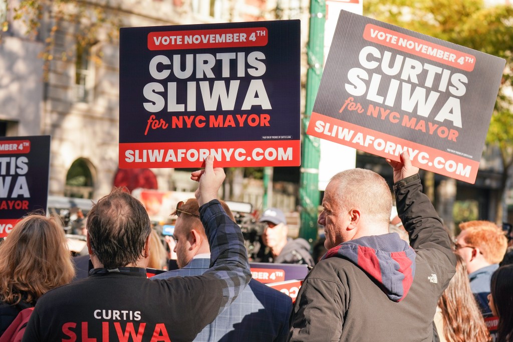 Two supporters hold campaign signs for Curtis Sliwa for NYC Mayor.
