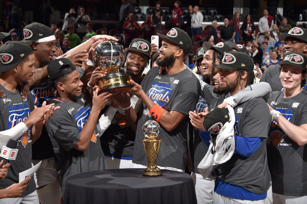 The New York Knicks basketball team celebrates winning the Eastern Conference Championship, holding up the championship trophy.