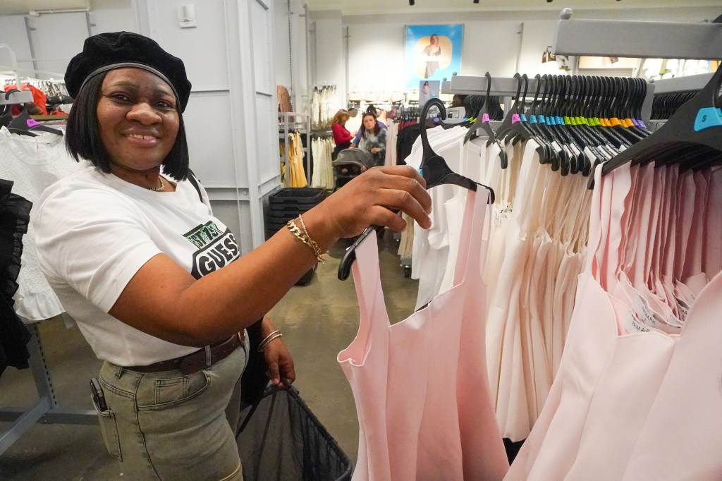 Wanda Holder, a sales associate, smiles while holding a garment at the Primark store opening.