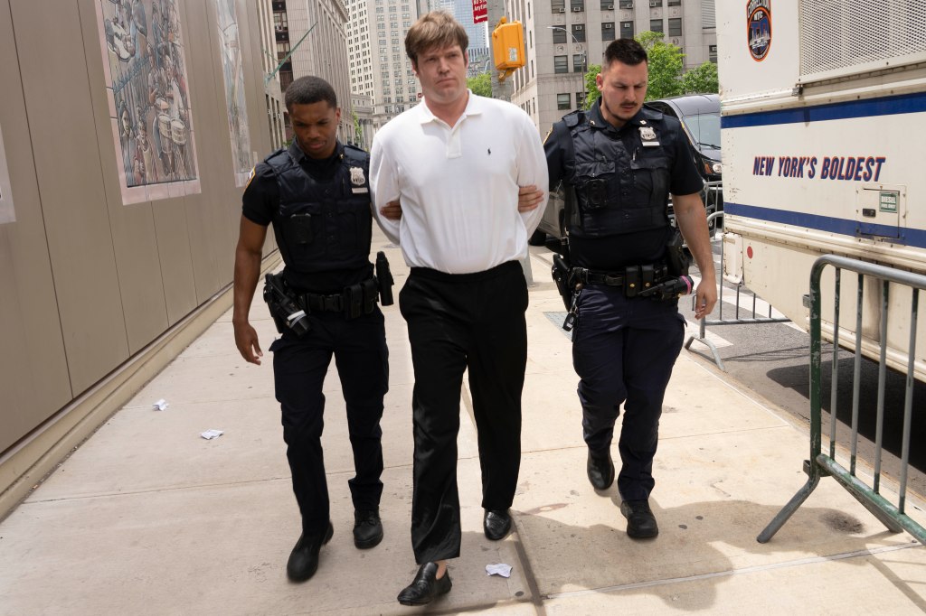 William Duplessie being escorted by two police officers.
