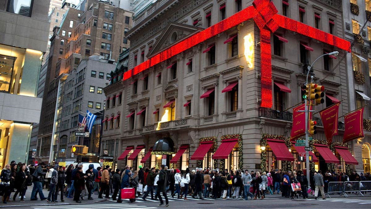 Shoppers crowd the sidewalk around the Cartier Mansion wrapped in a red bow for the holidays, on Fifth Avenue in New York