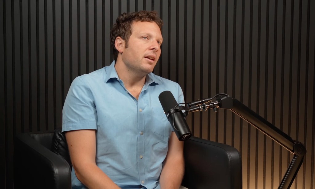 New York Magazine writer Ross Barkan speaks into a microphone.