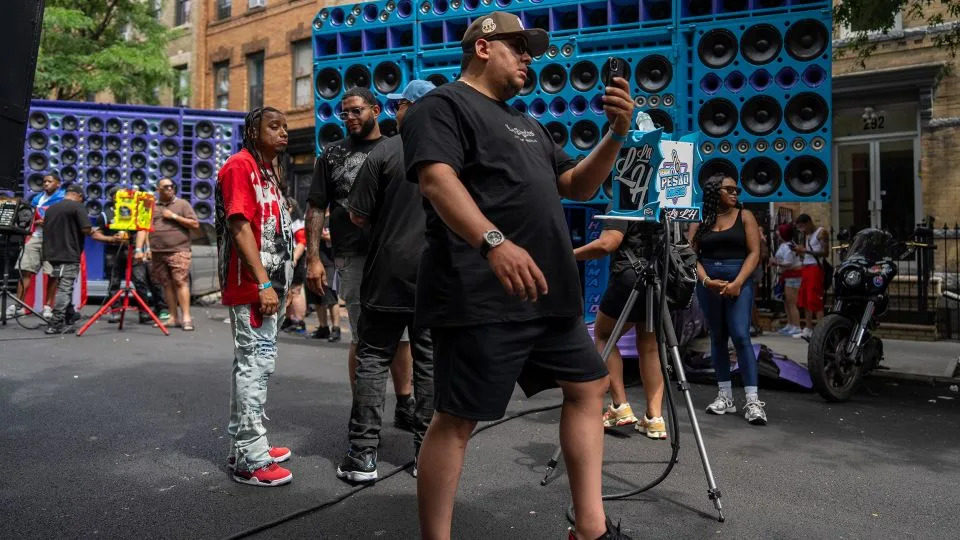 Attendees walk past sound sound systems blasting reggaeton music. - David Dee Delgado for CNN