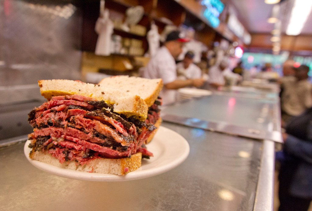 A close-up of a hot pastrami sandwich on a white plate at Katz's Delicatessen.