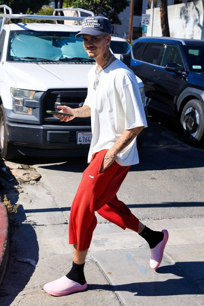 Romeo Beckham walking in red trousers