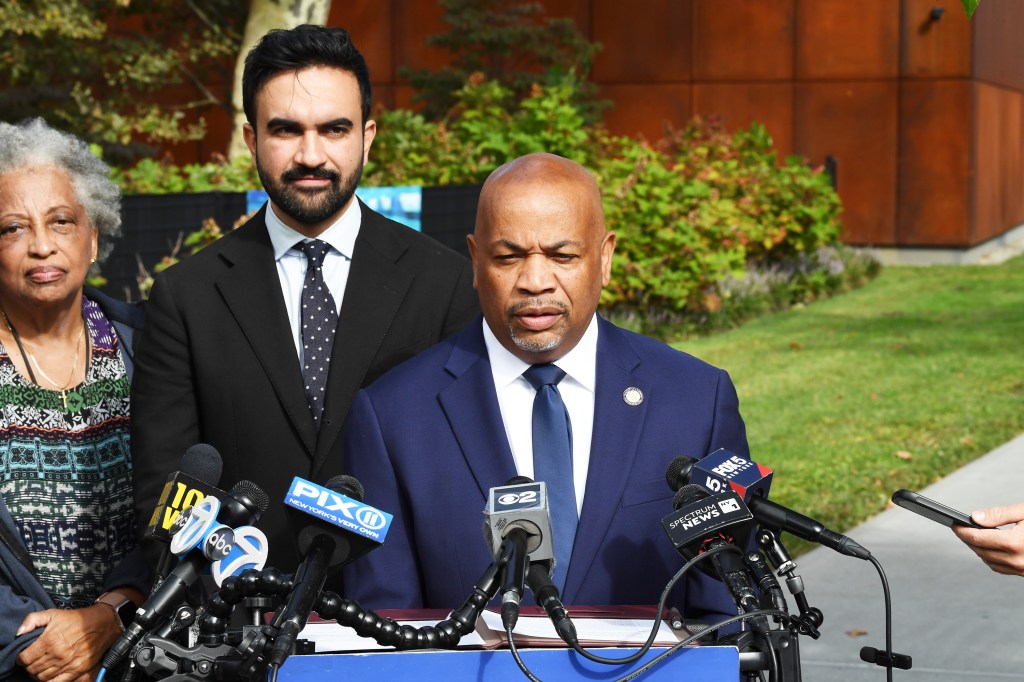 NYC Mayoral candidate Zohran Mamdani, Assembly Speaker Carl Heastie, and another individual stand behind microphones at a press conference.