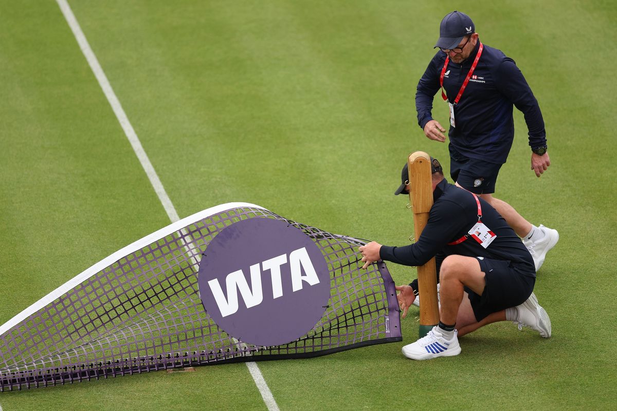 The groundsmen put down the WTA net as rain starts to fall at Queen's