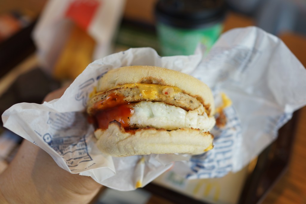 A hand holding a McDonald's Egg McMuffin.
