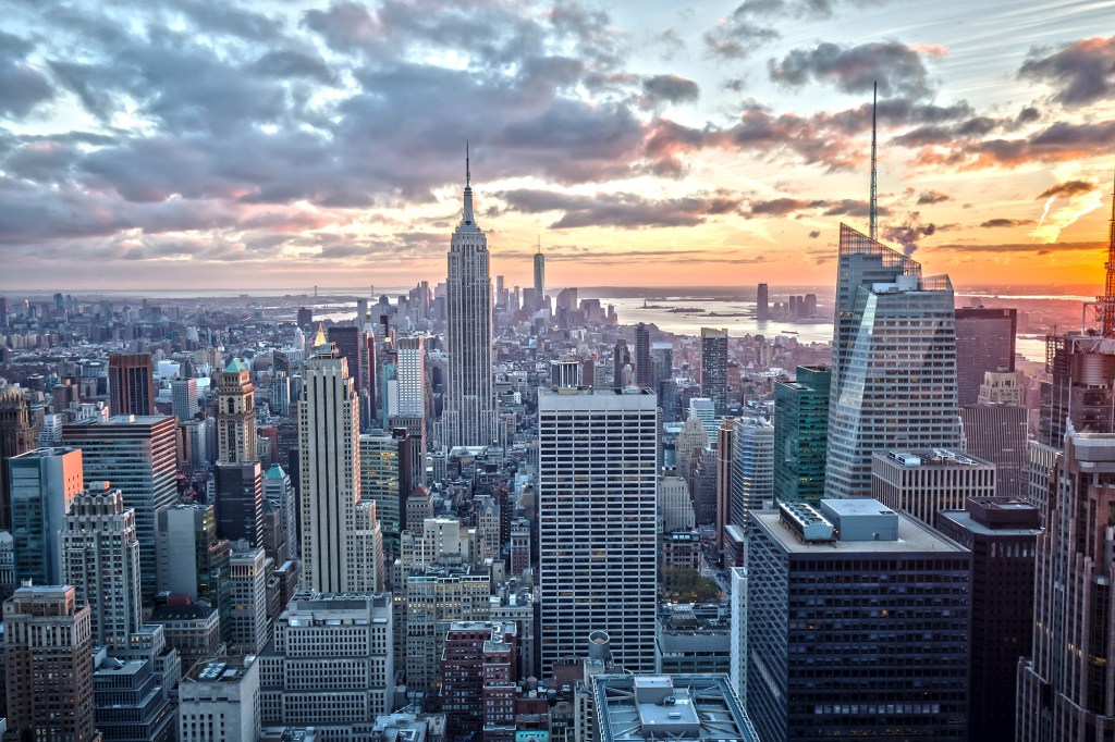New York City skyline at sunset, with the Empire State Building prominent among other skyscrapers.
