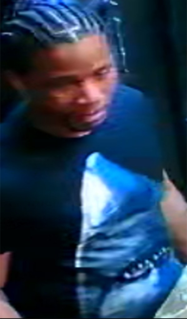 A man with braided hair wearing a dark t-shirt with a blue and white shark graphic.