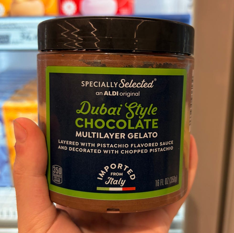 Hand holding a jar of Dubai Style Chocolate Gelato in front of mochi ice cream boxes in a store freezer.