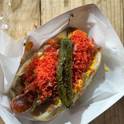 A Cali dog is wrapped in bacon and covered in...