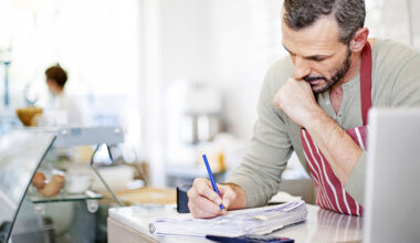 Small Business owner calculating at the counter of his cafe.