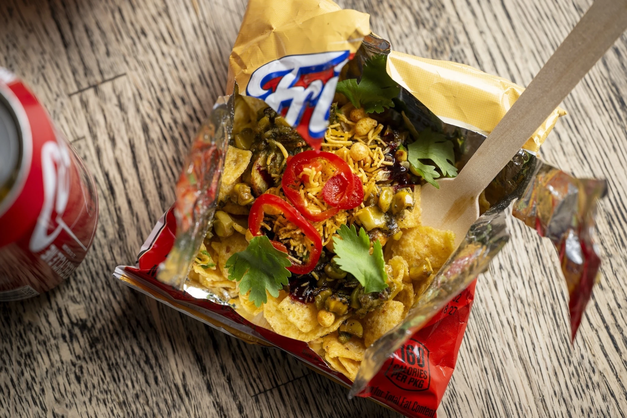 An open Fritos bag with chaat and peppers