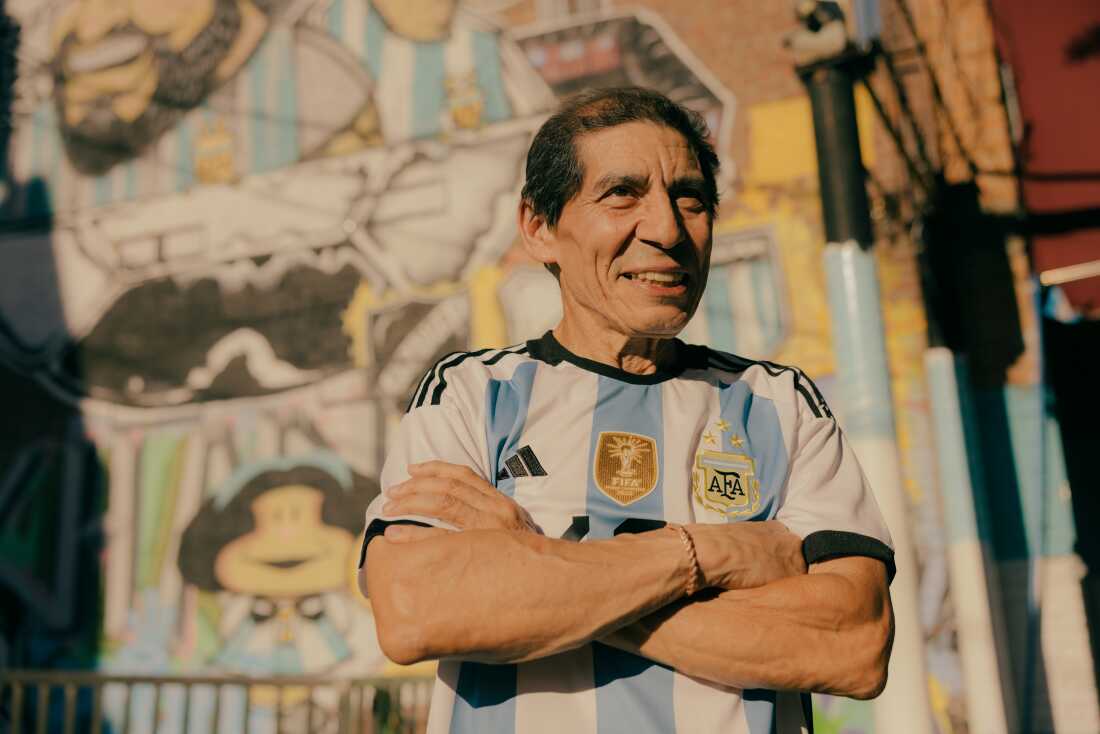 Juan David Iza, opens a sticker pack of Panini World Cup players along Roosevelt Avenue and 98 Street, as residents navigate the bustling avenue in Queens, New York, U.S., on Sunday, June 7, 2026. CREDIT: José A. Alvarado Jr. for NPR, @josealvarado
