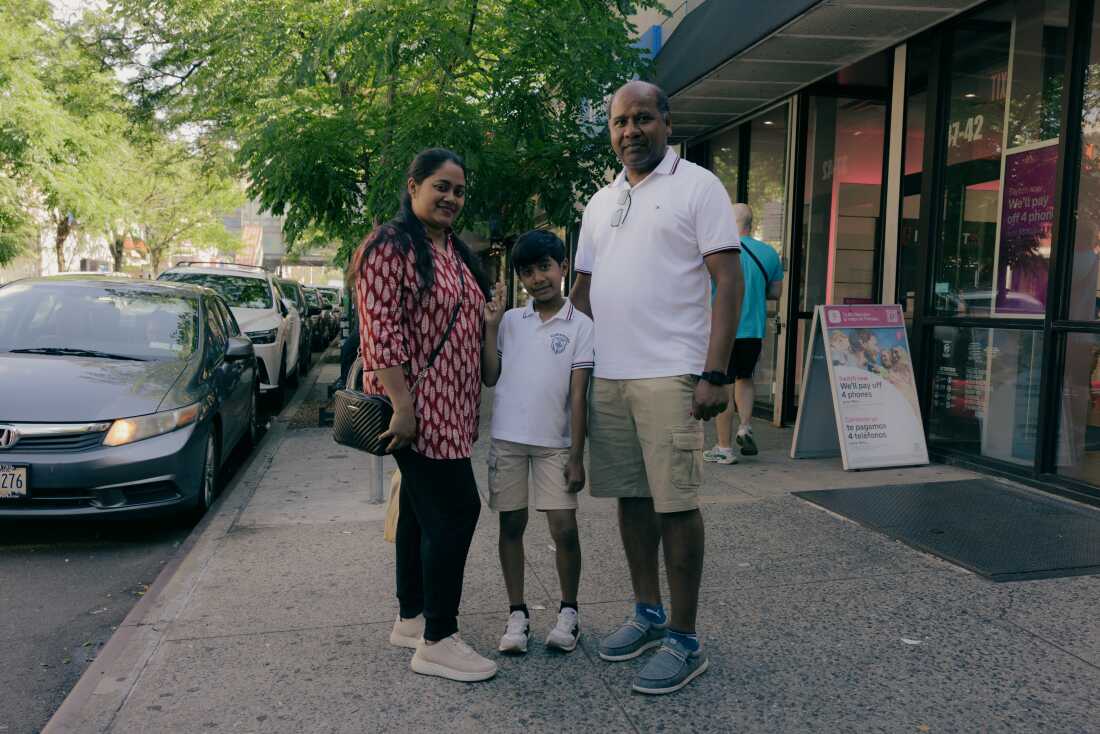 As commotion fills the air of Diversity Plaza, Gloria Rozario, left, Wilson Costa, center, and Shipu D. Costa, right, stand for a portrait outside of Diversity Plaza on 74 Street in Queens, New York, U.S., on Sunday, June 7, 2026. CREDIT: José A. Alvarado Jr. for NPR, @josealvarado