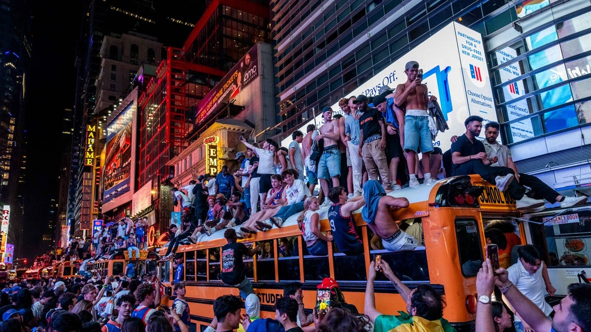 New York Knicks fans climb on buses as they celebrate after they win the NBA Finals in Times Square on June 14, 2026 in New York City.