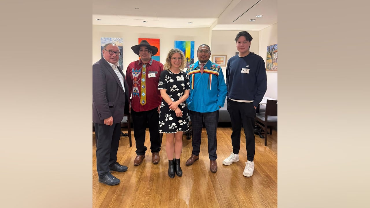 Five people are seen standing in a room.