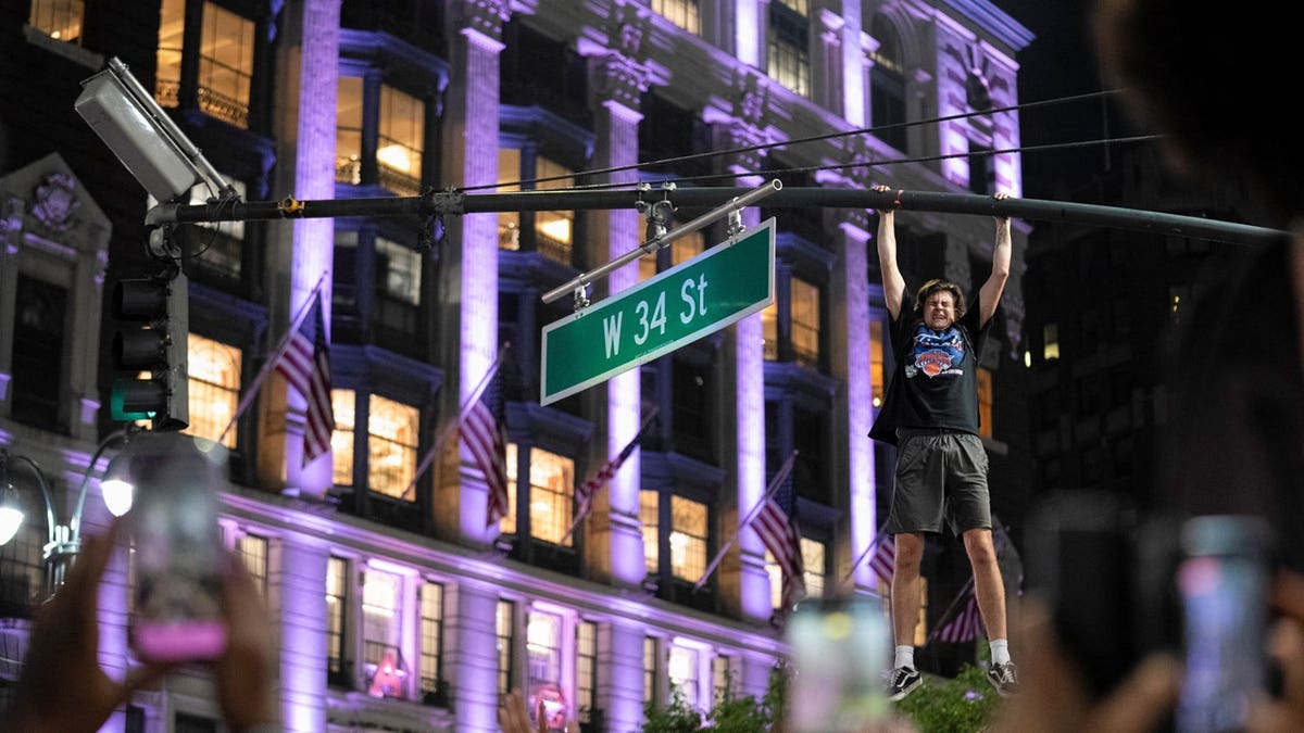 A fan celebrates the New York Knicks' win against the San Antonio Spurs in Game 5 of the NBA Finals, on a street near Madison Square Garden, in New York City, U.S., June 14, 2026.