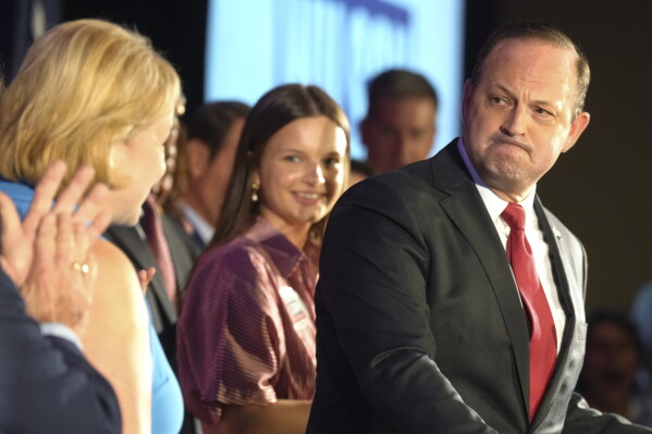 South Carolina Attorney General Alan Wilson, right, looks back at his wife, Jennifer, as he speaks to supporters celebrating his GOP gubernatorial runoff victory in a hotel ballroom on Tuesday, June 23, 2026, in Columbia, S.C. (AP Photo/Meg Kinnard)