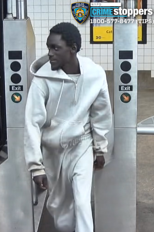 Suspect in a white hooded sweatshirt and pants at a subway turnstile.