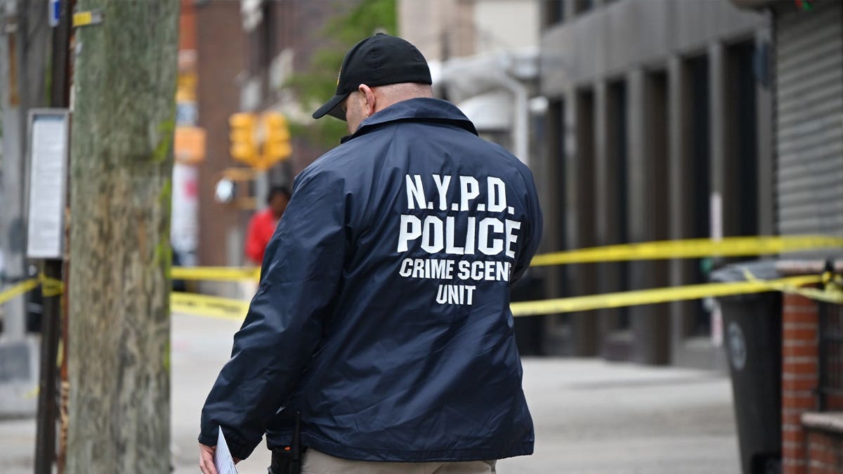 nypd officer walks through a crime scene