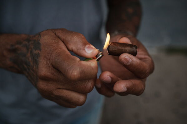 A man lights a cigar outside the grandstand at Aqueduct Racetrack in the Queens borough of New York, Saturday, June 27, 2026. (AP Photo/Andres Kudacki)