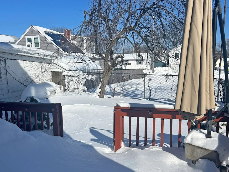 A snow-covered deck and backyard.