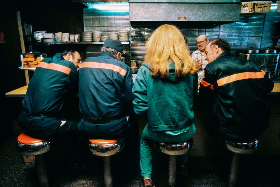 Four people sitting on stools at a diner counter.