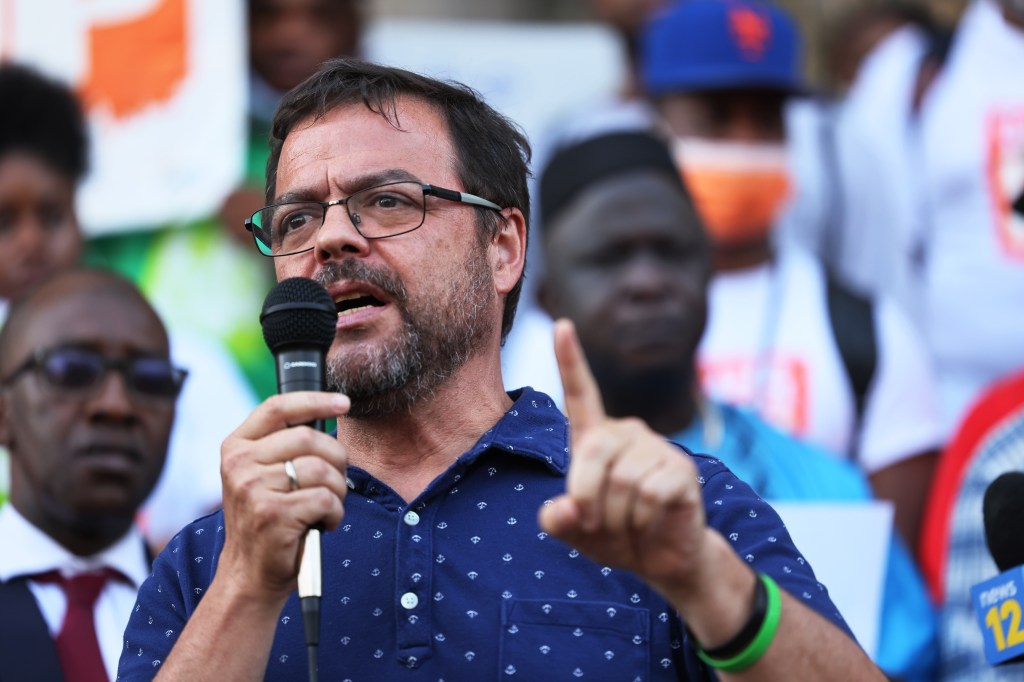 State Senator Luis Sepulveda speaking into a microphone with his finger raised at the "Stand Up Against Gun Violence" rally.