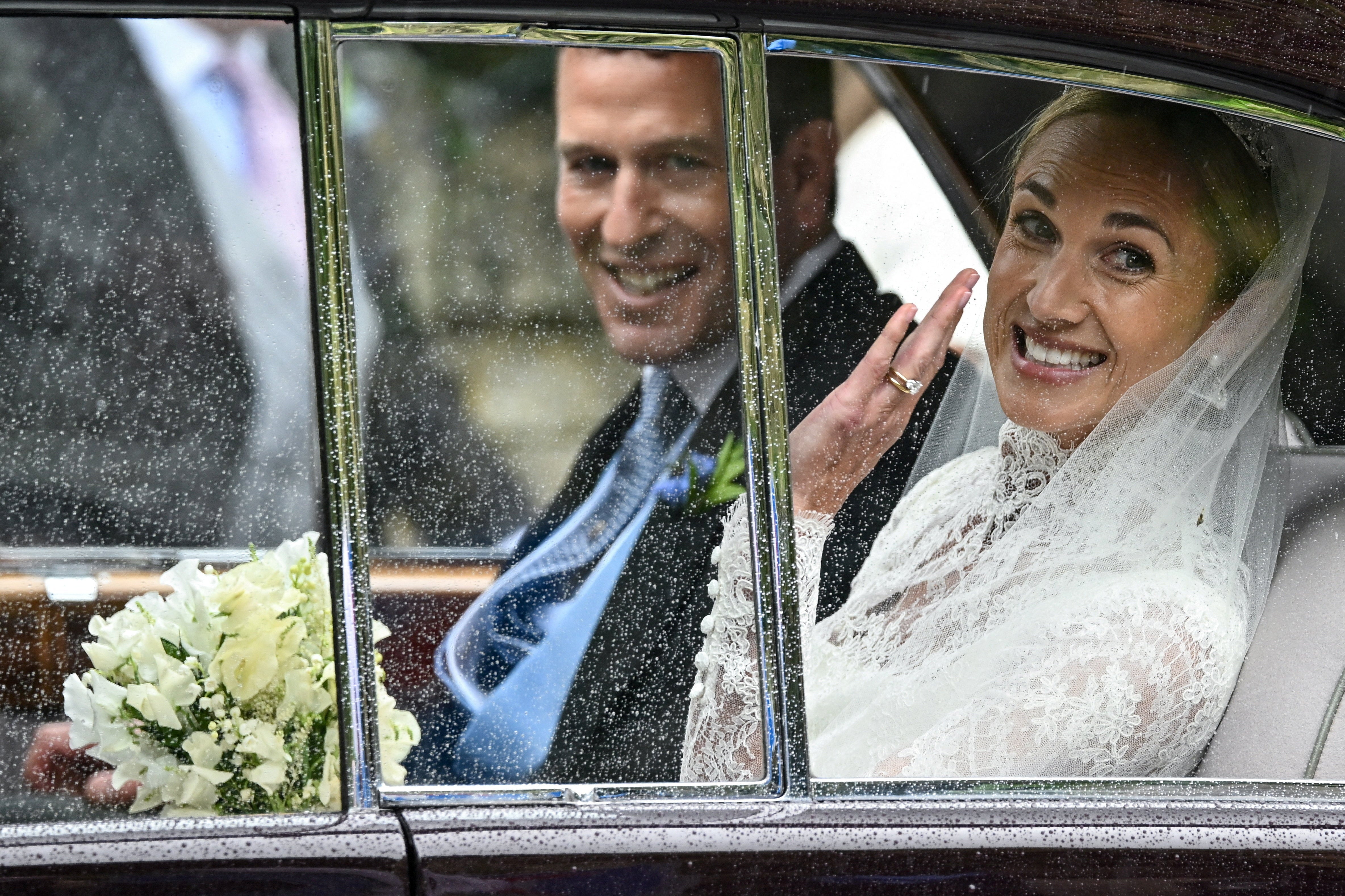 Harriet Sperling waves from a vehicle as she sits with Peter Phillips