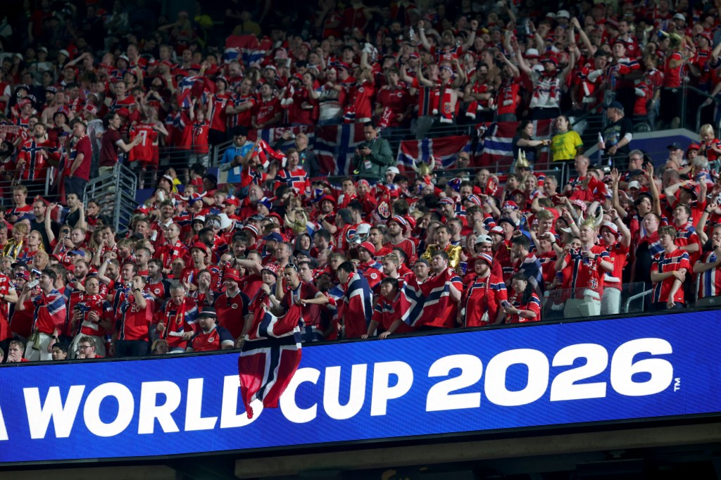 Thousands of Norway fans cheer for their team at MetLife Stadium during Norway's 3-2 victory over Senegal in a 2026 FIFA World Cup Group I match in East Rutherford, New Jersey, on Monday, June 22, 2026. A blue sign with white writing says, "World Cup 2026."