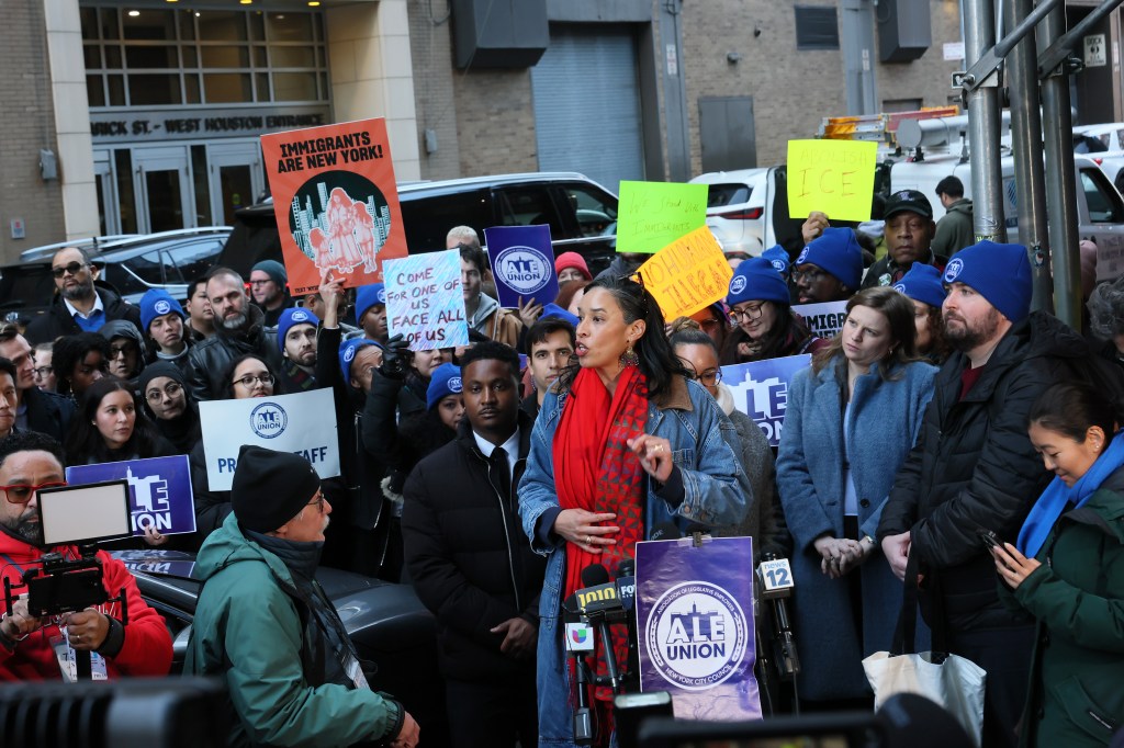 Councilmember Sandy Nurse speaks at a press conference surrounded by people holding signs that read "Immigrants Are New York!" and "Abolish ICE."