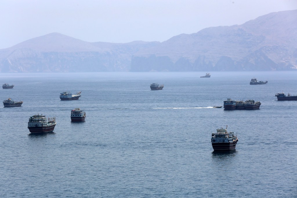 Many ships and boats in the Strait of Hormuz near Khasab, Oman, with mountains in the background.