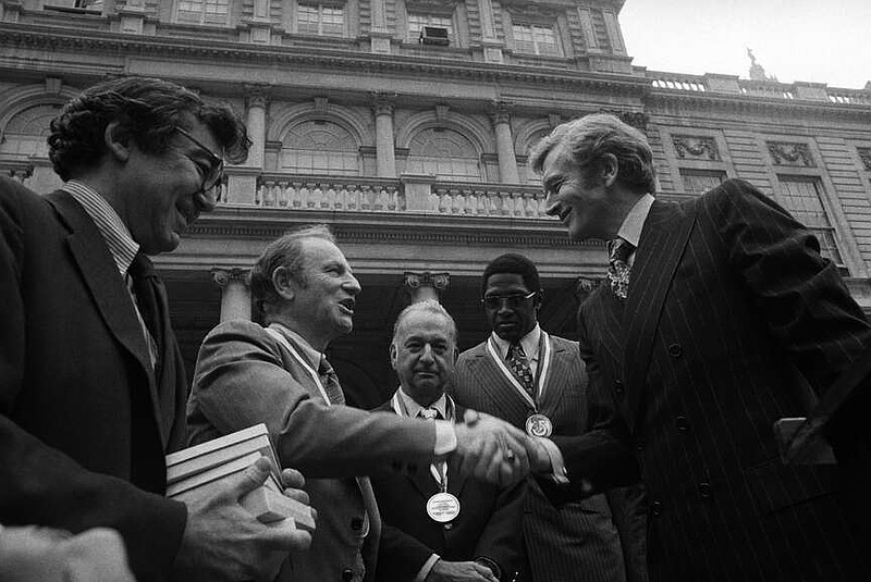 FILE - New York Mayor John Lindsay, right, congratulates Red Holzman, coach of the New York Knicks, after presenting the city's diamond jubilee medals to Holzman and other members of the Knicks team on the steps of City Hall on May 15, 1973. Shown with the mayor are Irving Felt, board chairman of Madison Square Garden, second from left, and Willis Reed, team captain, next to Lindsay. (AP Photo/Anthony Camerano, File)