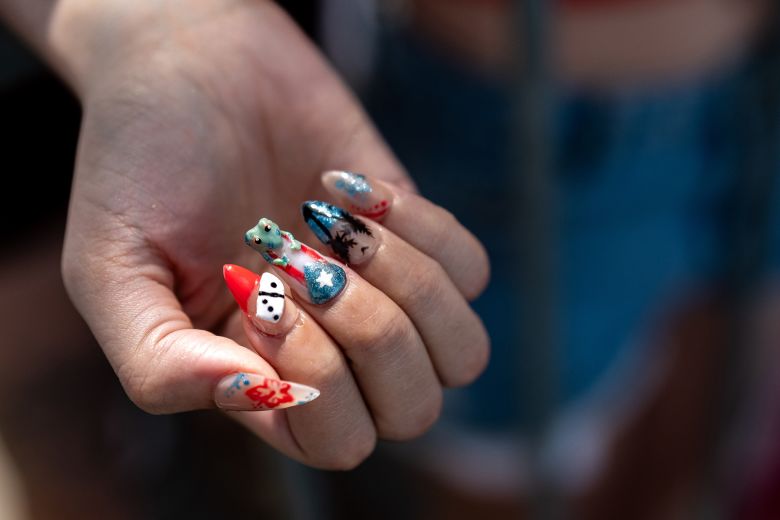 A festival-goer shows their Puerto Rico-themed custom nails, featuring dominos, the flor de maga, and the coqui frog.